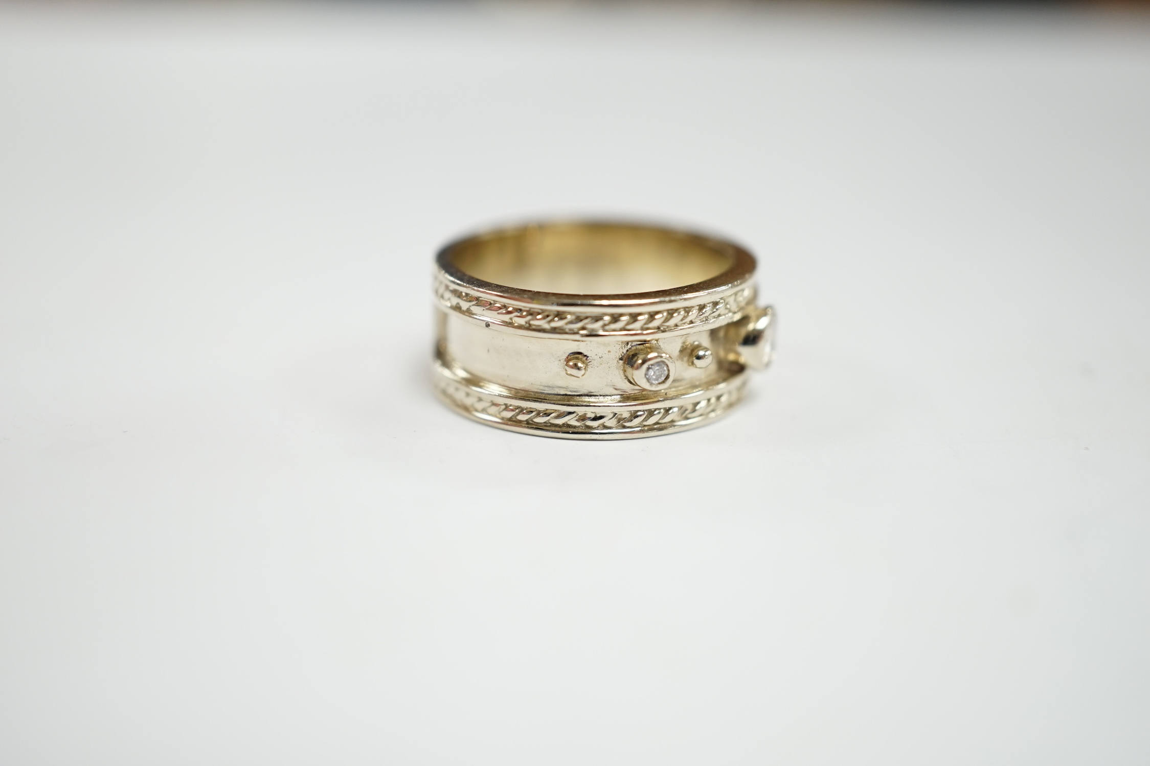 A modern 14k white metal and three stone collet set diamond set band, size M, gross weight 7.5 grams.